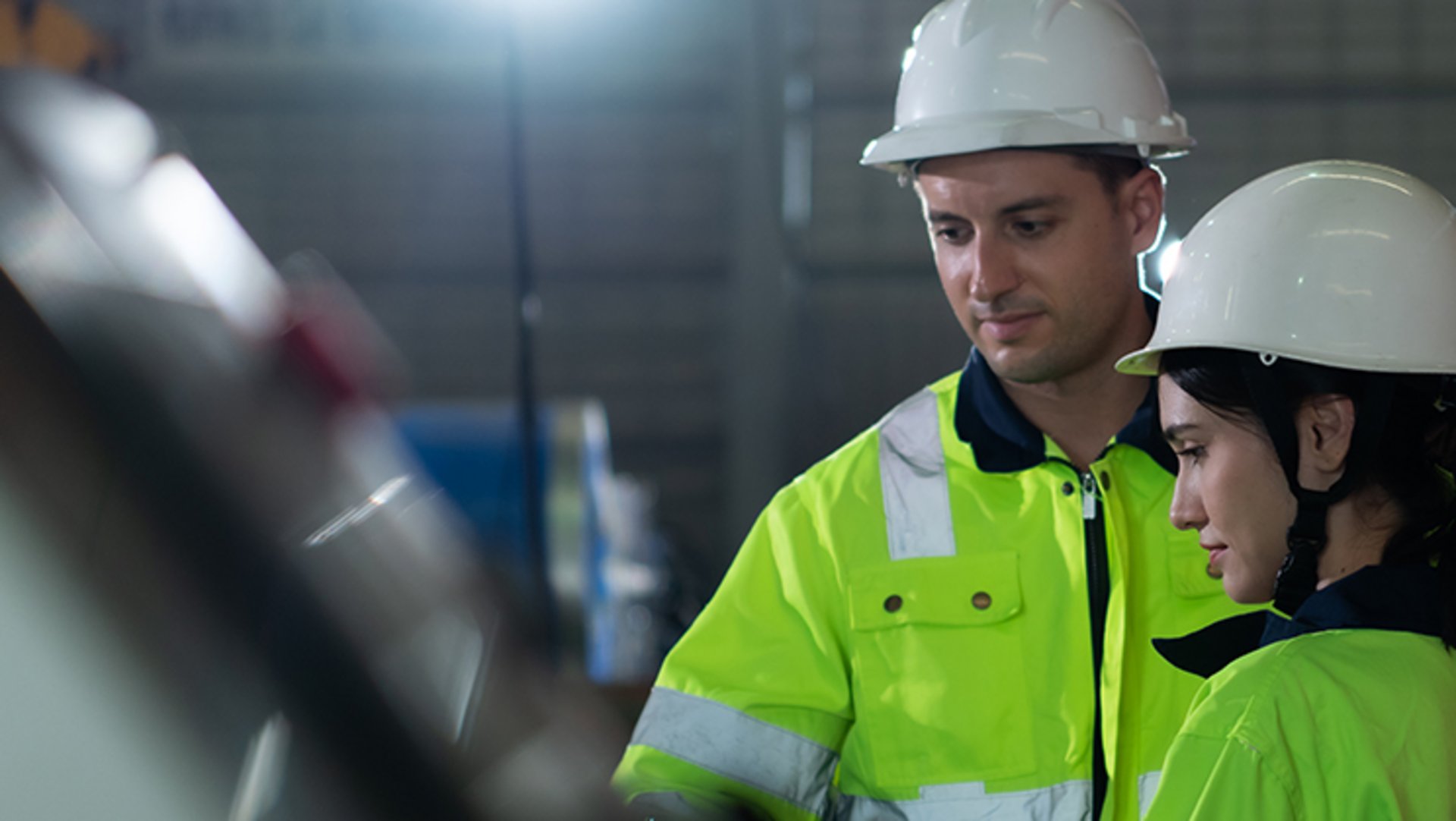 Eine junge Ingenieurin und ein Maschinenführer besprechen sich an der Steuereinheit der Papiermaschine.