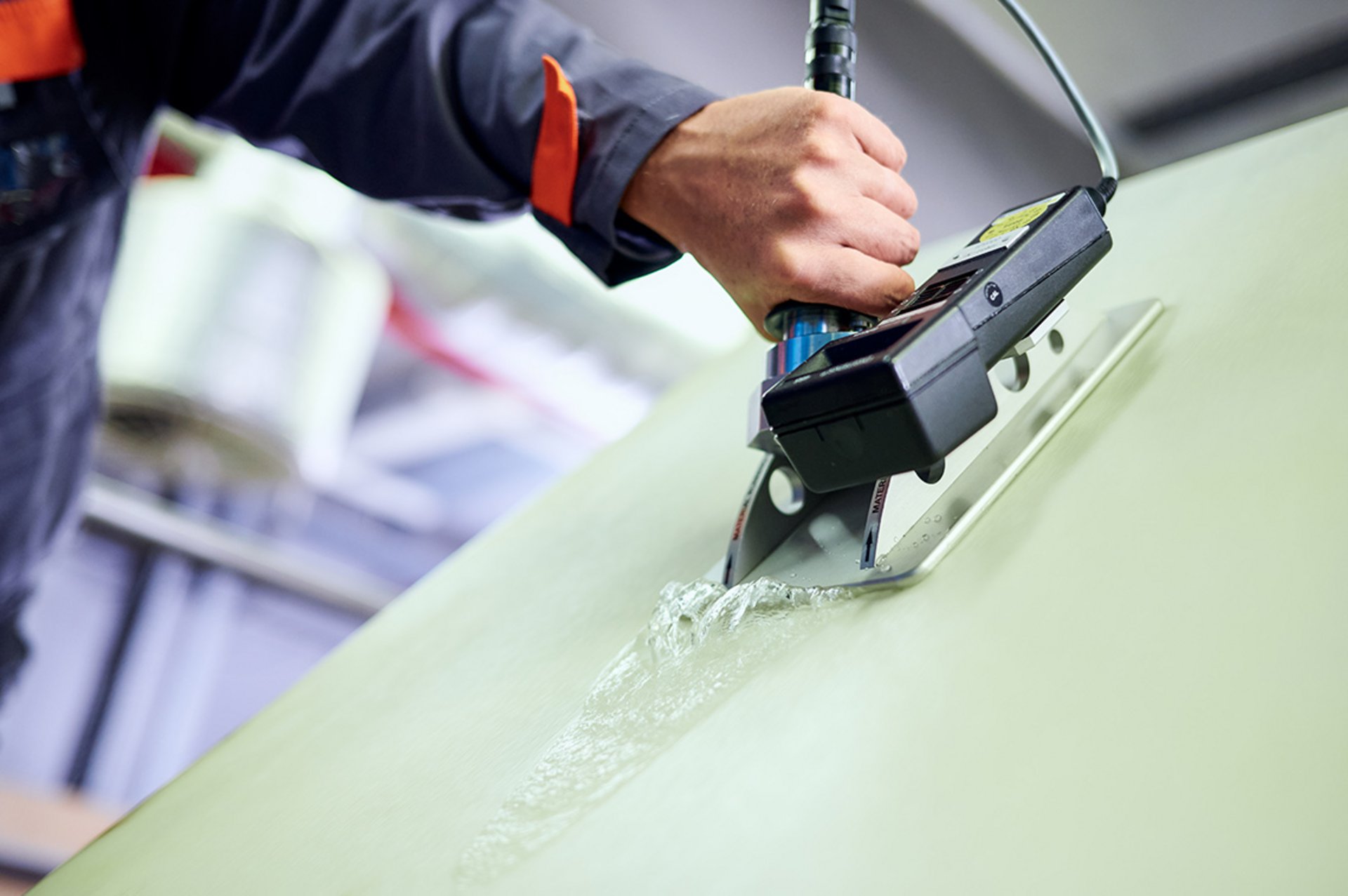 Ein Mitarbeiter des technischen Services von Heimbach misst die Spannung der Bespannung einer laufenden Papiermaschine.