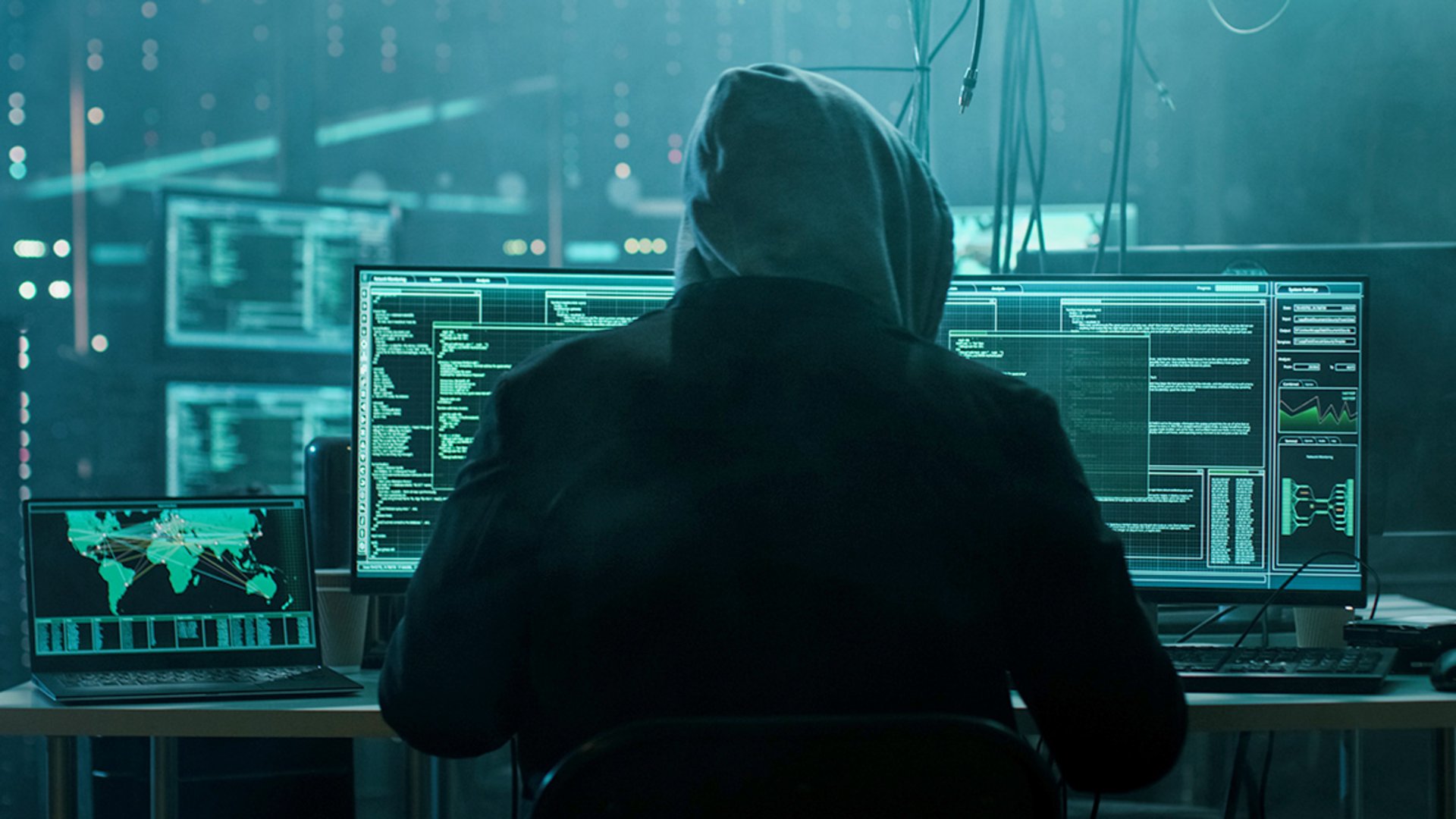 Ein Cyberkrimineller in sitzt in einem dunklen Raum und startet einen Cyberangriff auf das Unternehmen T-Systems / Deutsche Telekom.