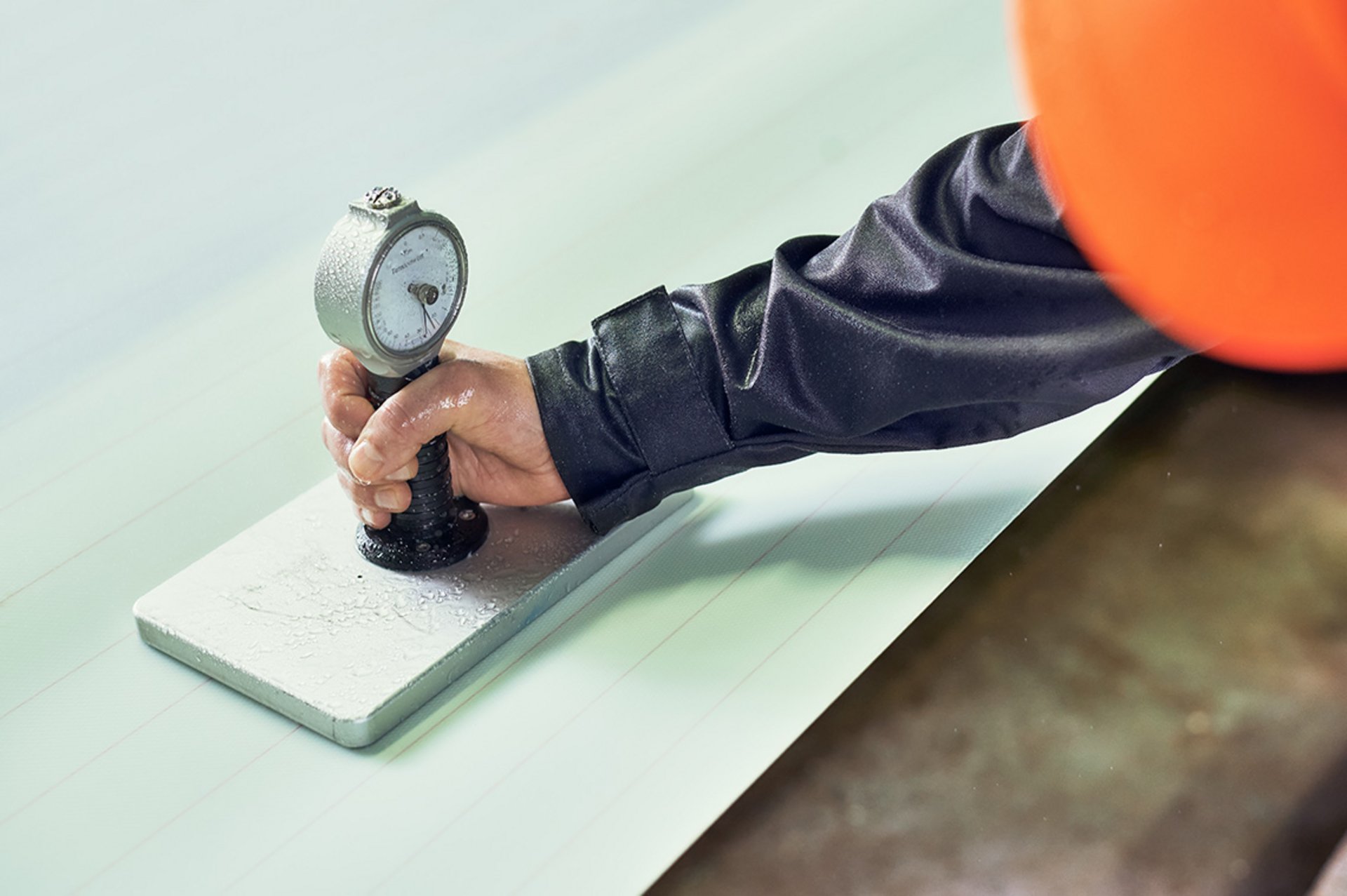 Ein Mitarbeiter des technischen Services von Heimbach nimmt eine Messung der Gewebespannung des Nasssiebes in der Papiermaschine vor.