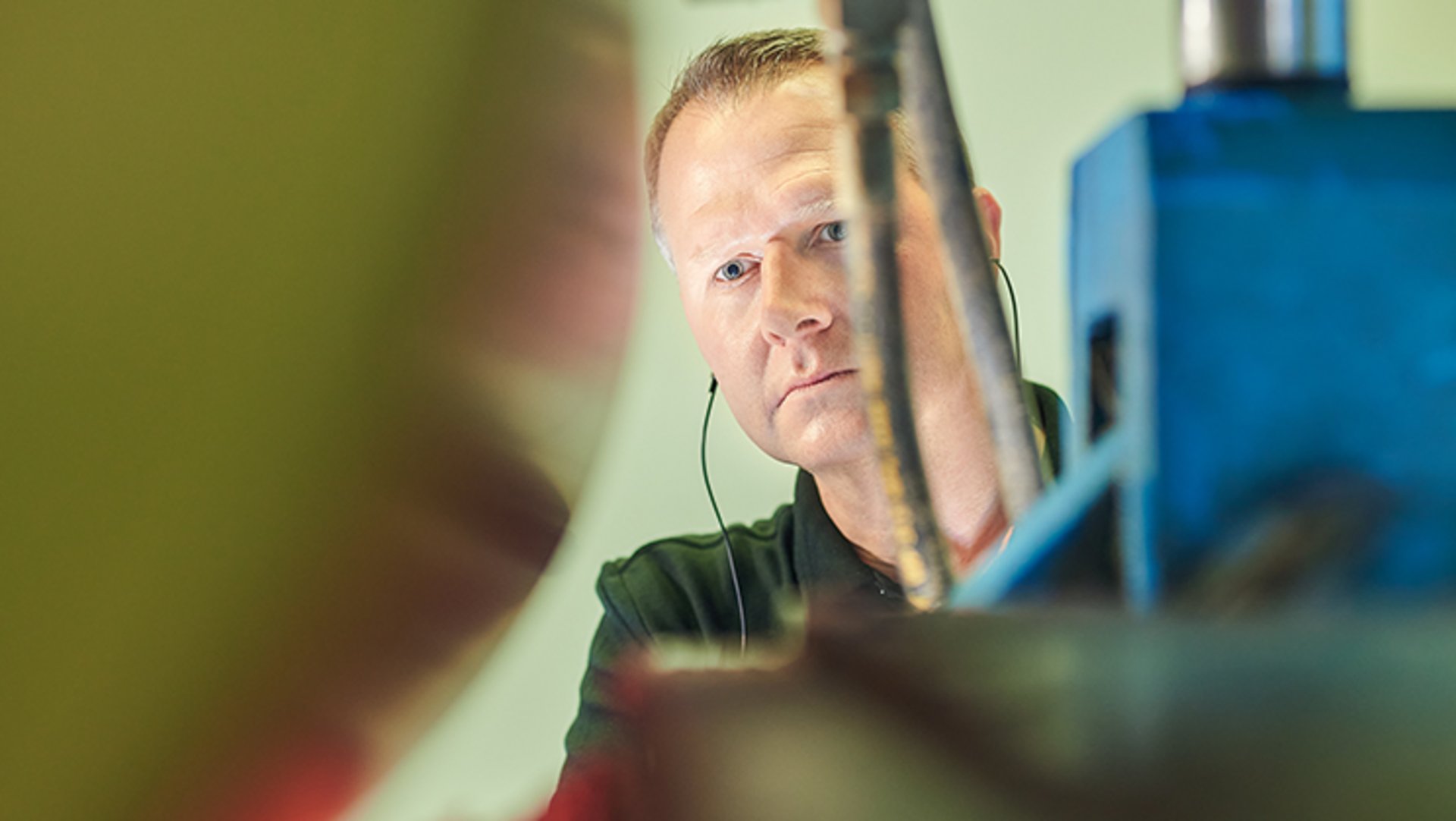 Ein Heimbach-Ingenieur blickt in das Walzenwerk einer Papiermaschine, um die Laufeigenschaften der Bespannung zu kontrollieren.