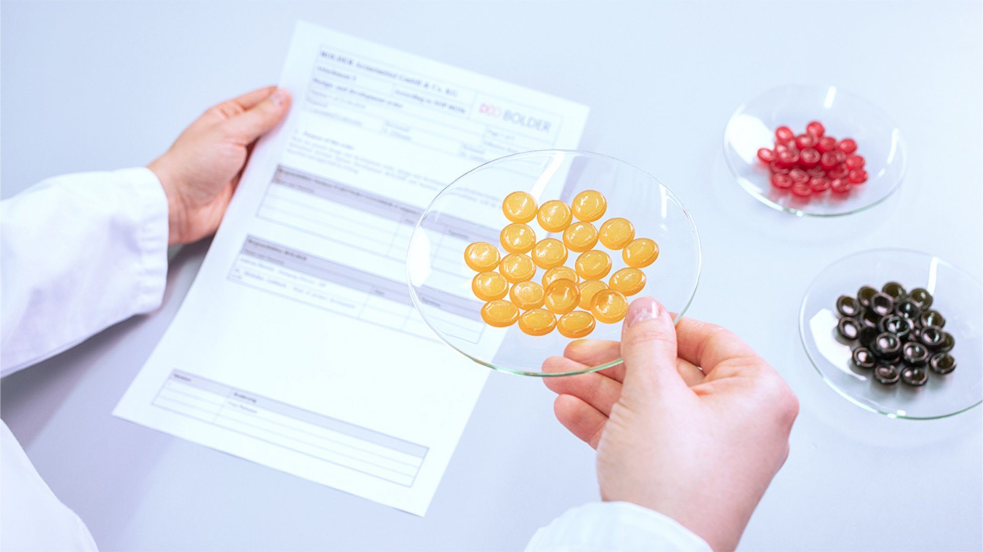 Die BOLDER Arzneimittel Bildwelt zeigt eine Produktentwicklerin, die Varianten von Pastillen Designs prüft.