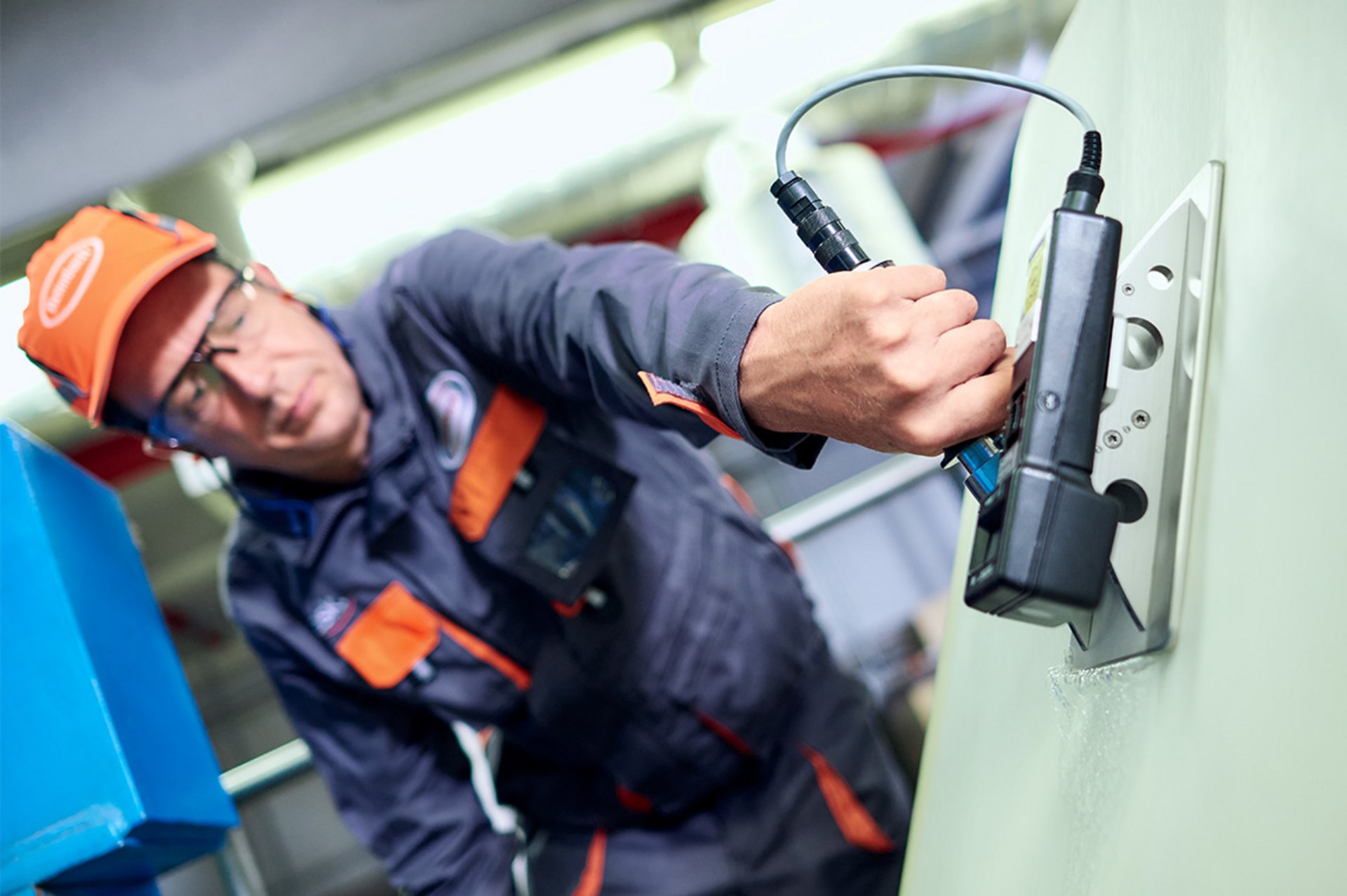 Ein Mitarbeiter des technischen Services nimmt am Filz einer laufenden Papiermaschine eine Spannungsmessung vor.